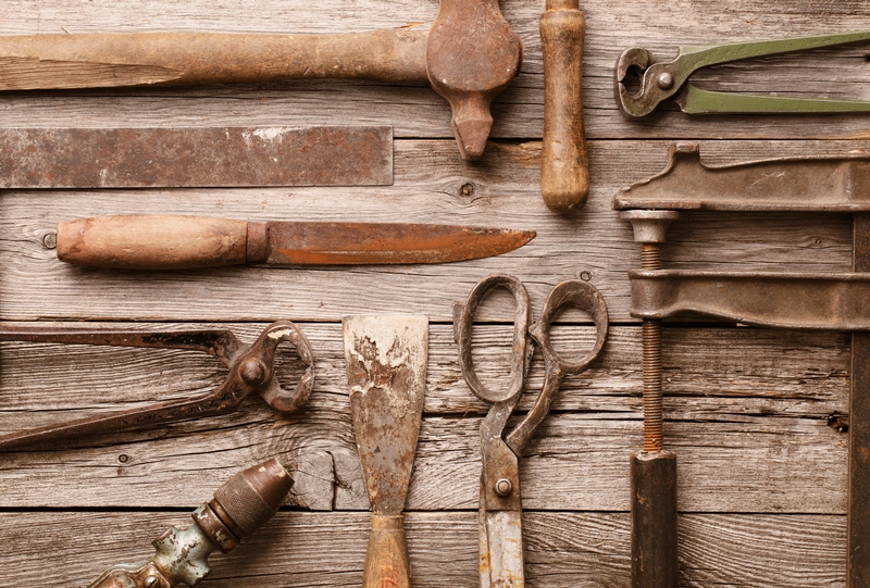 A collection of old weathered tools laid out on a wooden work table.